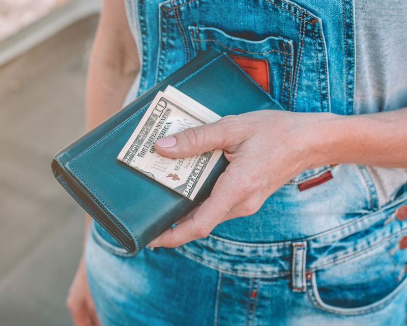 Woman in overalls with wallet in hand